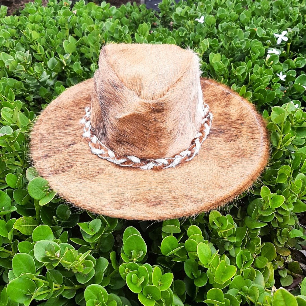 Brown fur hat with a white band on a green leaf background