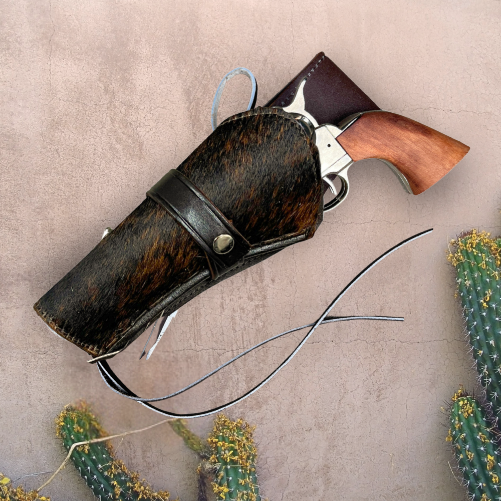 Cowhide leather holster with a gun on a textured beige background with cacti.