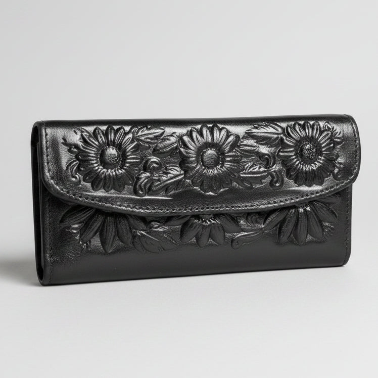 Black leather wallet with floral embossing held by a hand on a gray carpeted floor.
