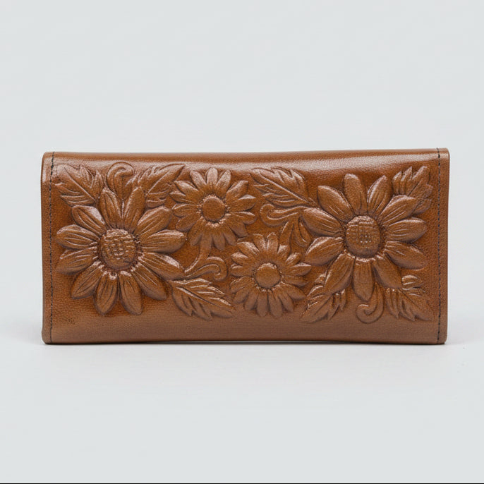 Brown leather wallet with floral patterns held in a hand against a blurred background