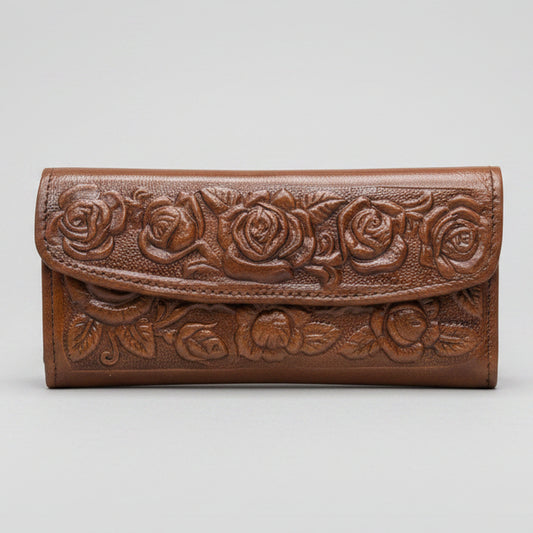 Brown leather wallet with floral patterns held by a hand against a blurred indoor background
