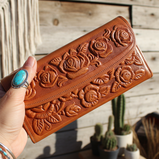 Brown leather wallet with floral embossing on a wooden surface